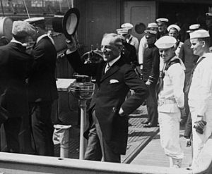 President Woodrow Wilson (center) waves his top hat from the deck of USS George Washington (ID # 3018), as she steamed up New York Harbor upon the President's return to the U.S. from the World War I peace conference in France, 8 July 1919. Photo by Unknown author - This file is a work of a sailor or employee of the U.S. Navy, taken or made as part of that person's official duties. As a work of the U.S. federal government, it is in the public domain in the United States., Public Domain, https://commons.wikimedia.org/w/index.php?curid=103723398