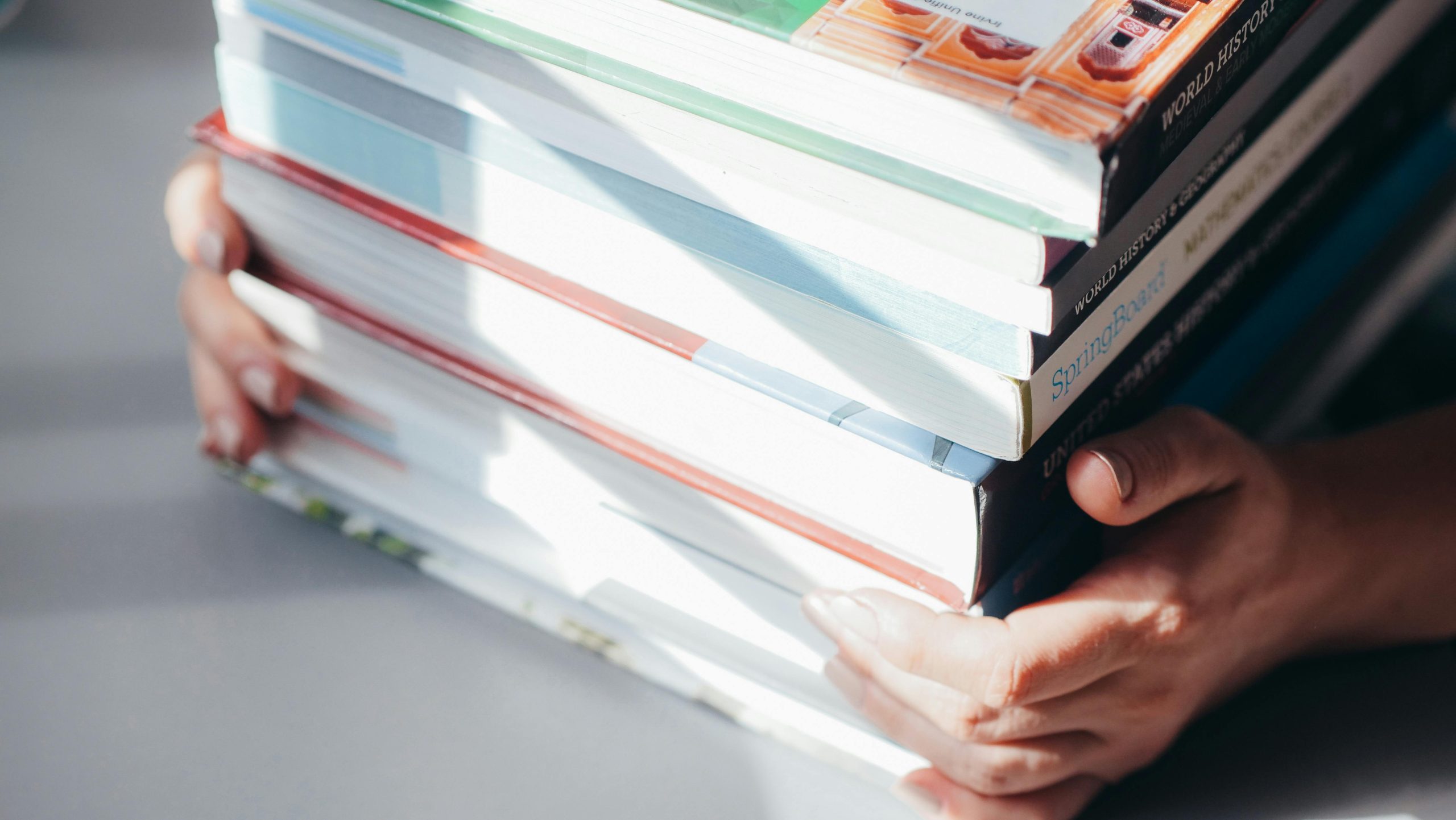 Textbooks. Image via Pexels.com https://www.pexels.com/photo/a-person-holding-a-stack-of-books-7054519/