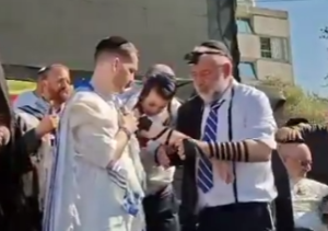Screengrab via Anash.org https://anash.org/freed-hostage-leads-mass-tefillin-in-the-heart-of-tel-aviv/