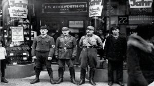 Judenboykott 1933-04-01 Berlin Anti-Semitic Anti-Jewish Nazi boycott Jewish businesses shops in Germany SA NSDAP brownshirts singing chanting blocking allegedly Jewish-founded FW Woolworth Koningstr Bundesarchiv. By Uncredited photographer; unidentified, anonymous or unknown author. No known copyright restrictions. - https://www.reddit.com/r/HistoryPorn/comments/1ayv8i/nazis_singing_to_encourage_a_boycott_of_the/Low resolution image posted on Reddit.com, allegedly copied from the Digital Picture Archives of the Federal Archives in Germany (Das Bundesarchiv), CC BY-SA 4.0, https://commons.wikimedia.org/w/index.php?curid=148445621